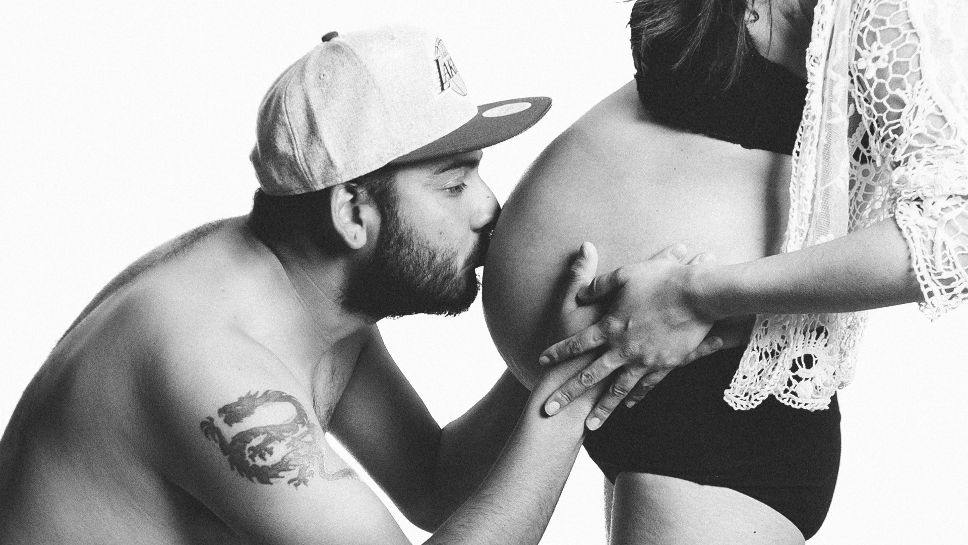 man kissing a pregnant belly